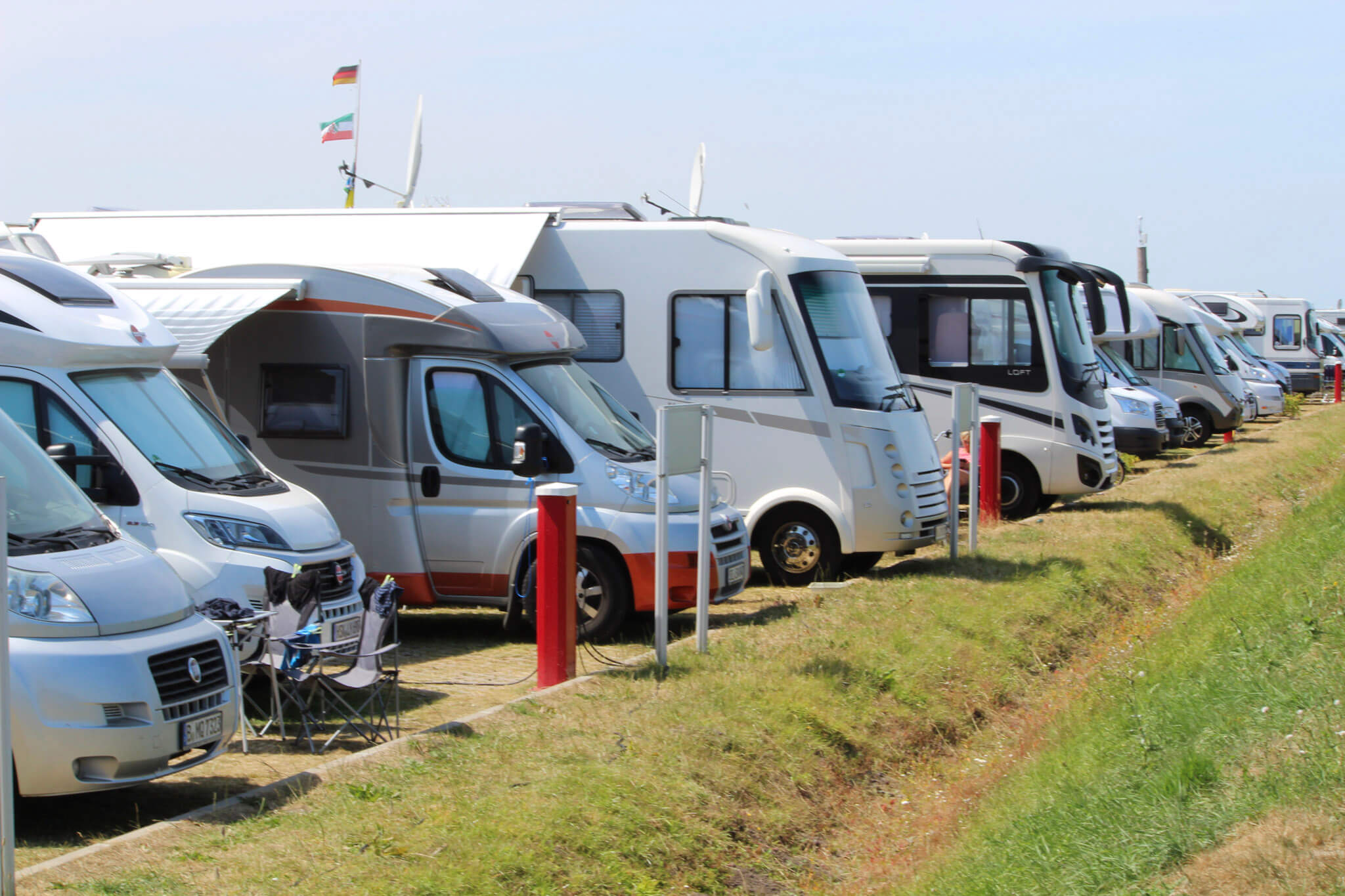 Mehrere Wohnmobile stehen auf einem Campingplatz aufgereiht