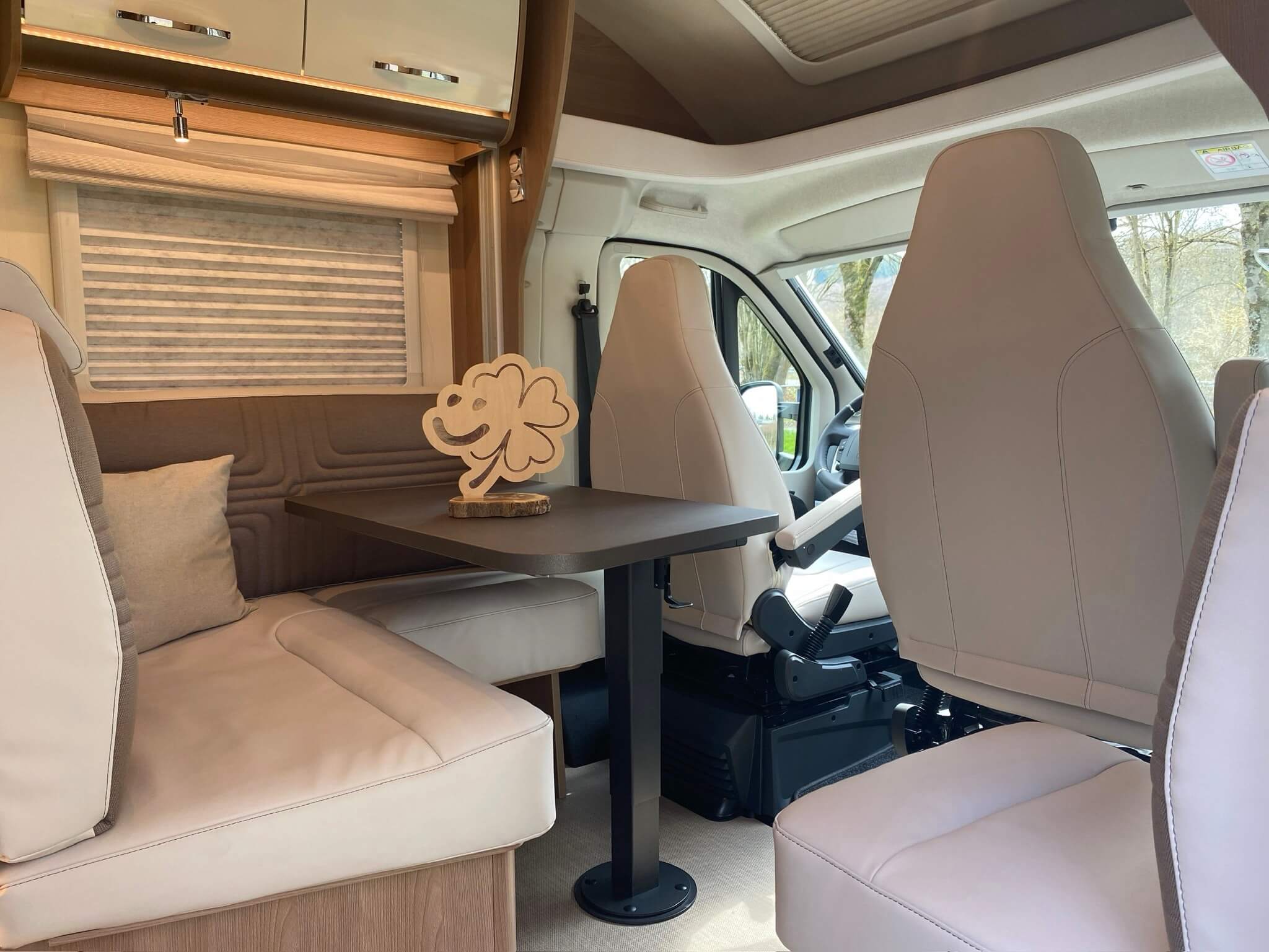 Blick in ein Wohnmobil, auf dem Tisch steht das Logo von glüxxmomente als Holz-Schild.